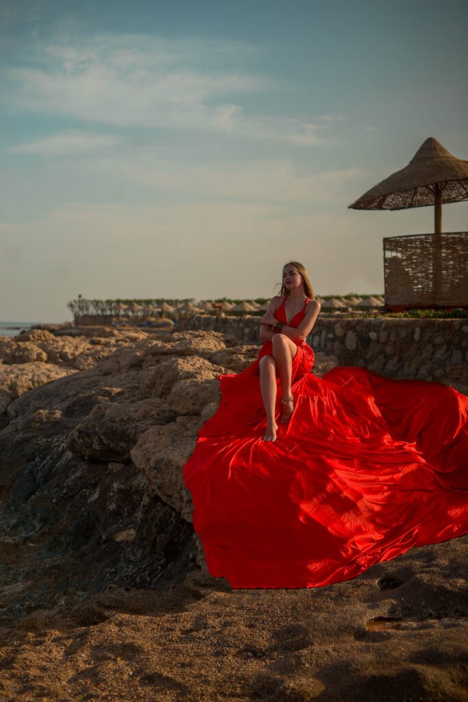 Woman in a red flying dress during a flying dress photoshoot in Sharm El Sheikh by the Red Sea.